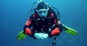 Scuba diver in gear under water blowing bubbles | Gunther Kia