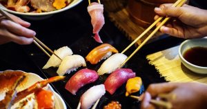4 people sharing a big plate of sushi using chopsticks in Fort Lauderdale, FL | Gunther Kia