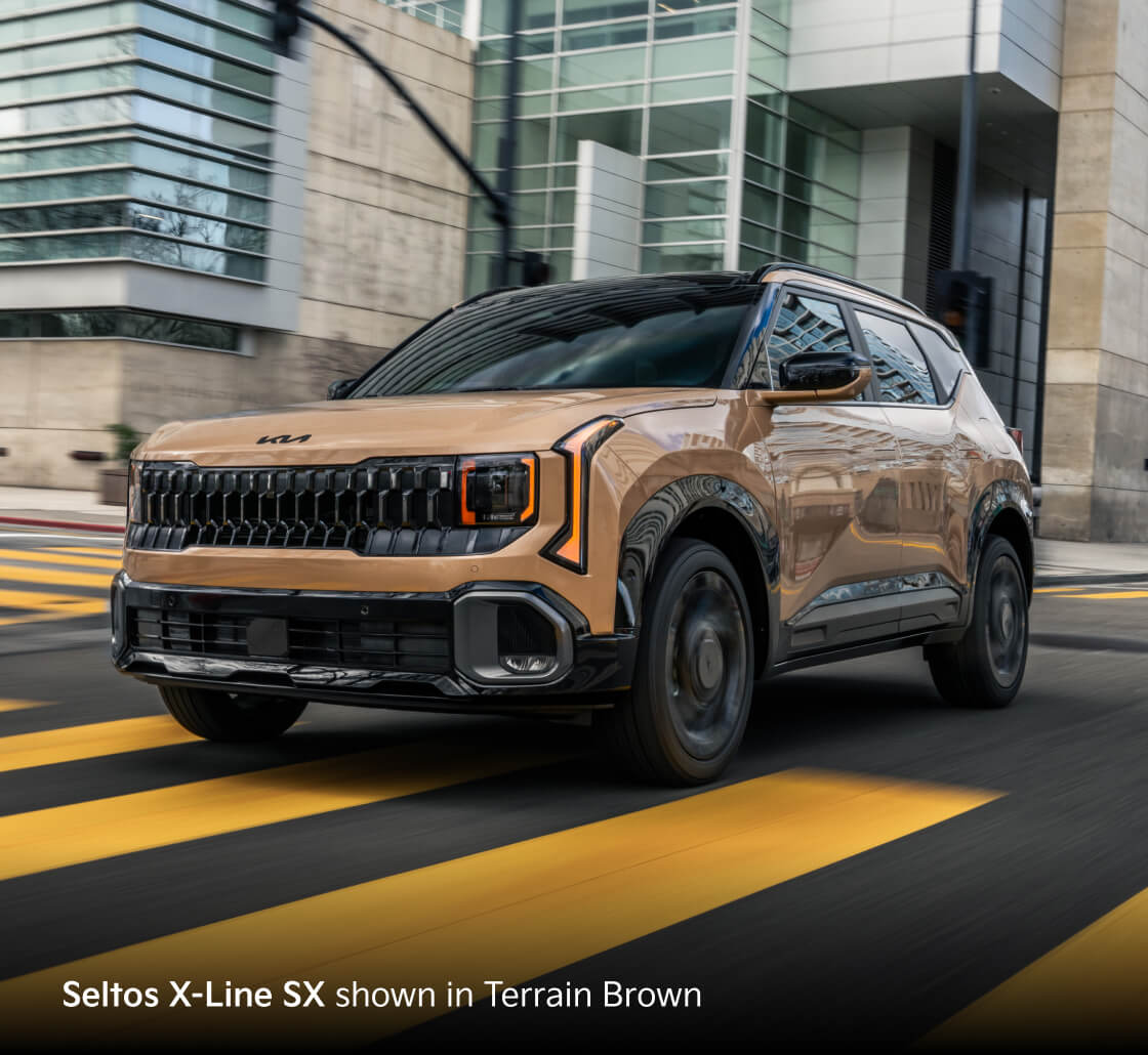 Seltos X-Line SX shown in Terrain Brown driving on a city street