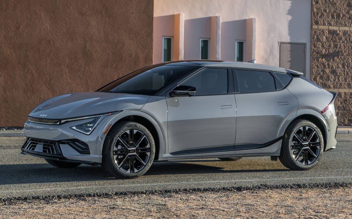 Silver Kia EV6 shown in a side profile parked outside a modern building in daylight.