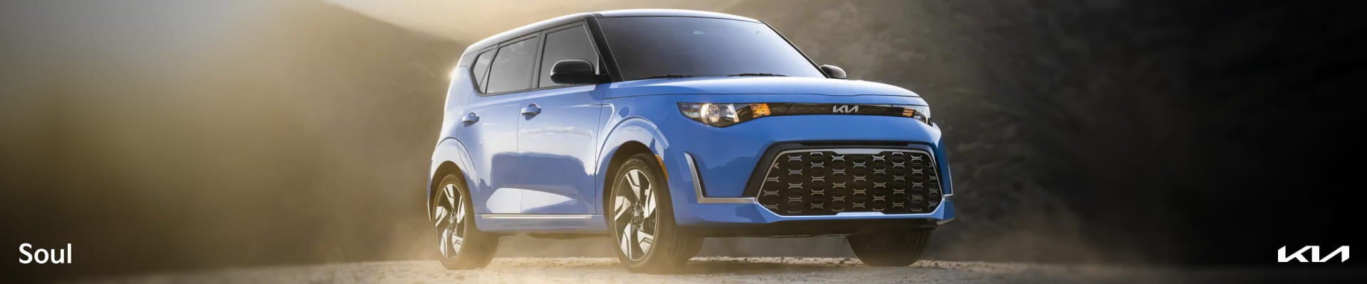 Blue Kia Soul shown from a front three-quarter angle against a mountainous outdoor backdrop.