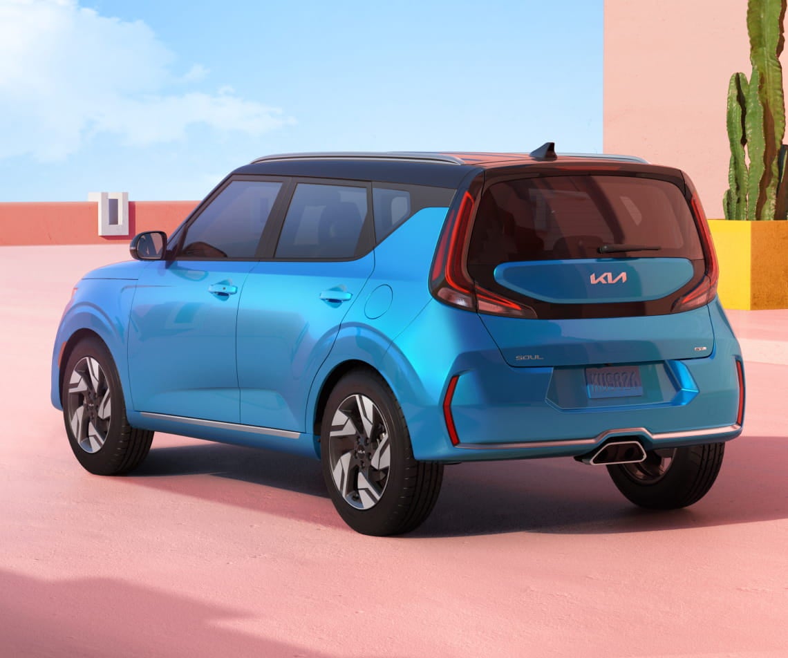Blue Kia Soul shown from a rear three-quarter angle against a colorful modern architectural backdrop.